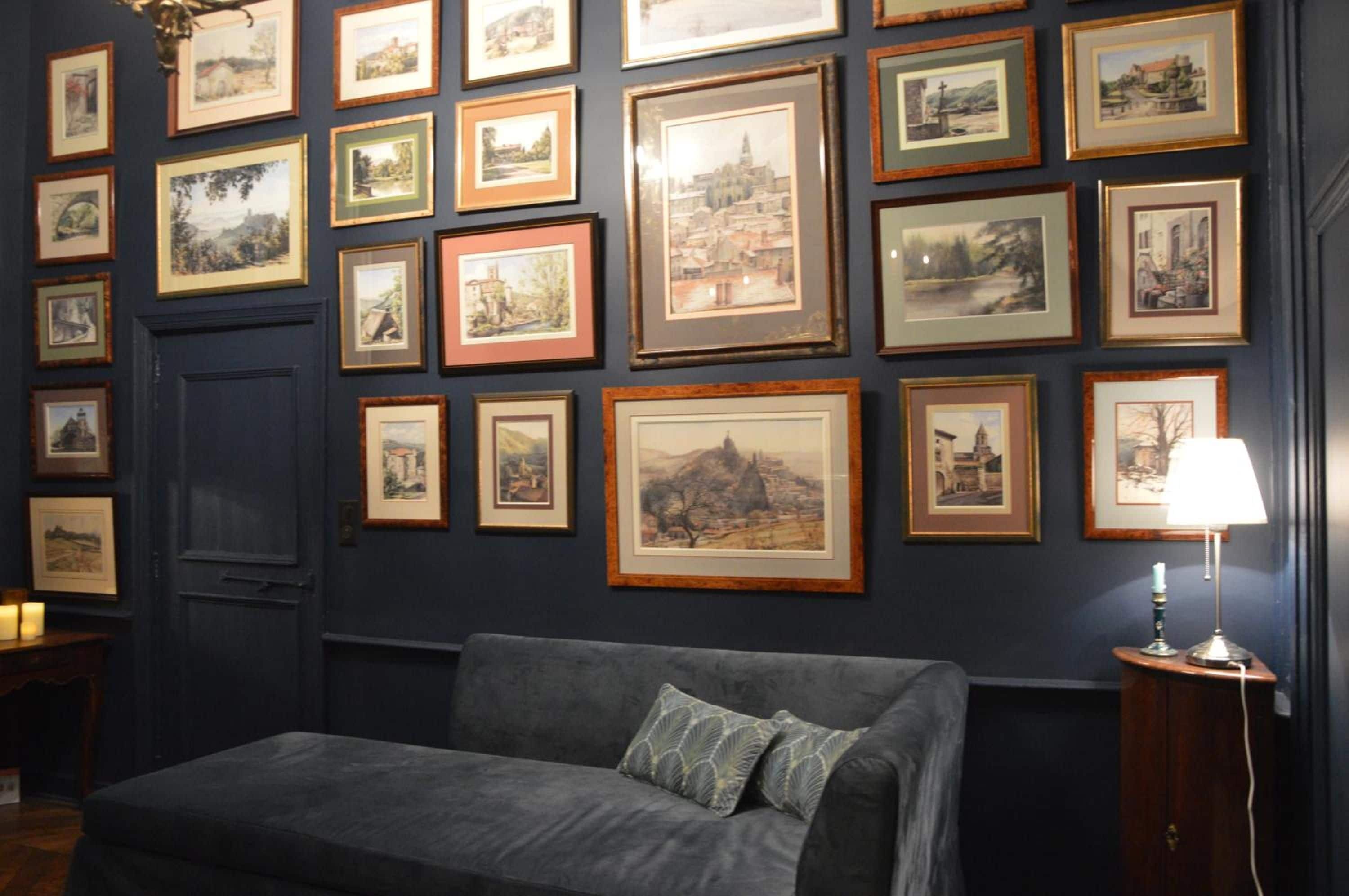 Una habitación con una pared azul oscuro decorada con pinturas enmarcadas de paisajes.