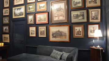 Una habitación con una pared azul oscuro decorada con pinturas enmarcadas de paisajes.