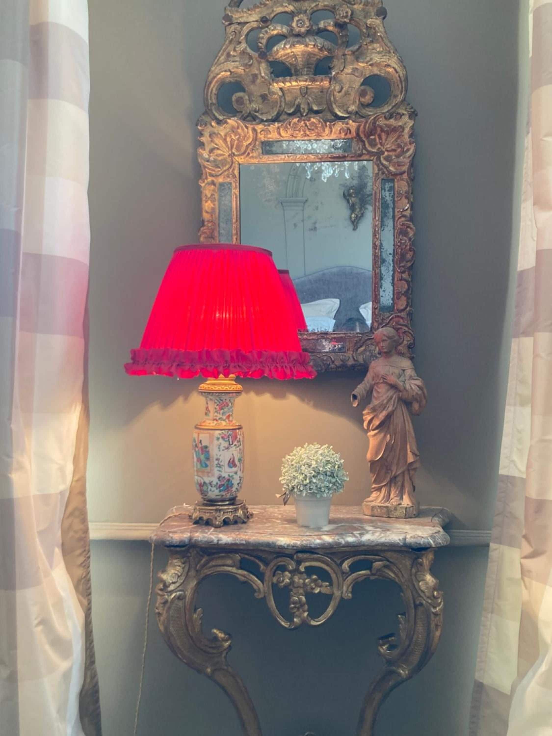A decorative console table with a red lamp, a small potted plant, and a statue.