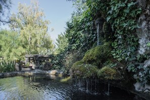 A tranquil garden with a pond, stone structures, and lush greenery. - Domaine de Chalaniat (La Sauvetat)