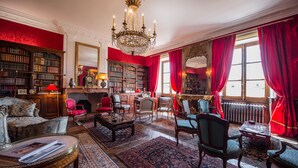 A classic library with ornate furniture, a grand chandelier, and red drapery. - Domaine de Chalaniat (La Sauvetat)
