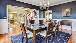 A dining area with a wooden table set for six, a chandelier, and a blue patterned rug. - Minutes from Downtown Cambridge | Private Dock | Pool | Kayaks (Cambridge)