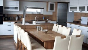Een moderne keuken met een centraal eiland, witte kastjes en een houten eettafel met stoelen.