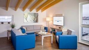Een moderne woonkamer met blauwe banken, een salontafel en een televisie waarop 'Baltic Sea Resort' staat.