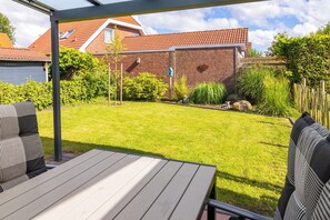 A patio with a table and chairs, a brick wall, and a well-maintained lawn.