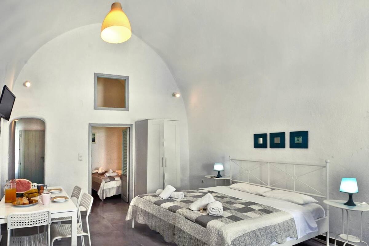 Une chambre avec un lit, un bureau où le petit-déjeuner est servi, une télévision et une petite fenêtre.