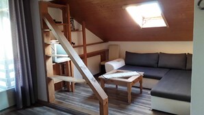 A cozy room with a wooden staircase, a sofa, and a small table. - Naturfreundepension Hagenberger für Erwachsene (Witzmannsberg)