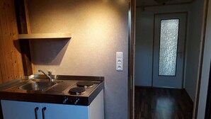A compact kitchen with a sink, stove, and a small window. - Naturfreundepension Hagenberger für Erwachsene (Witzmannsberg)