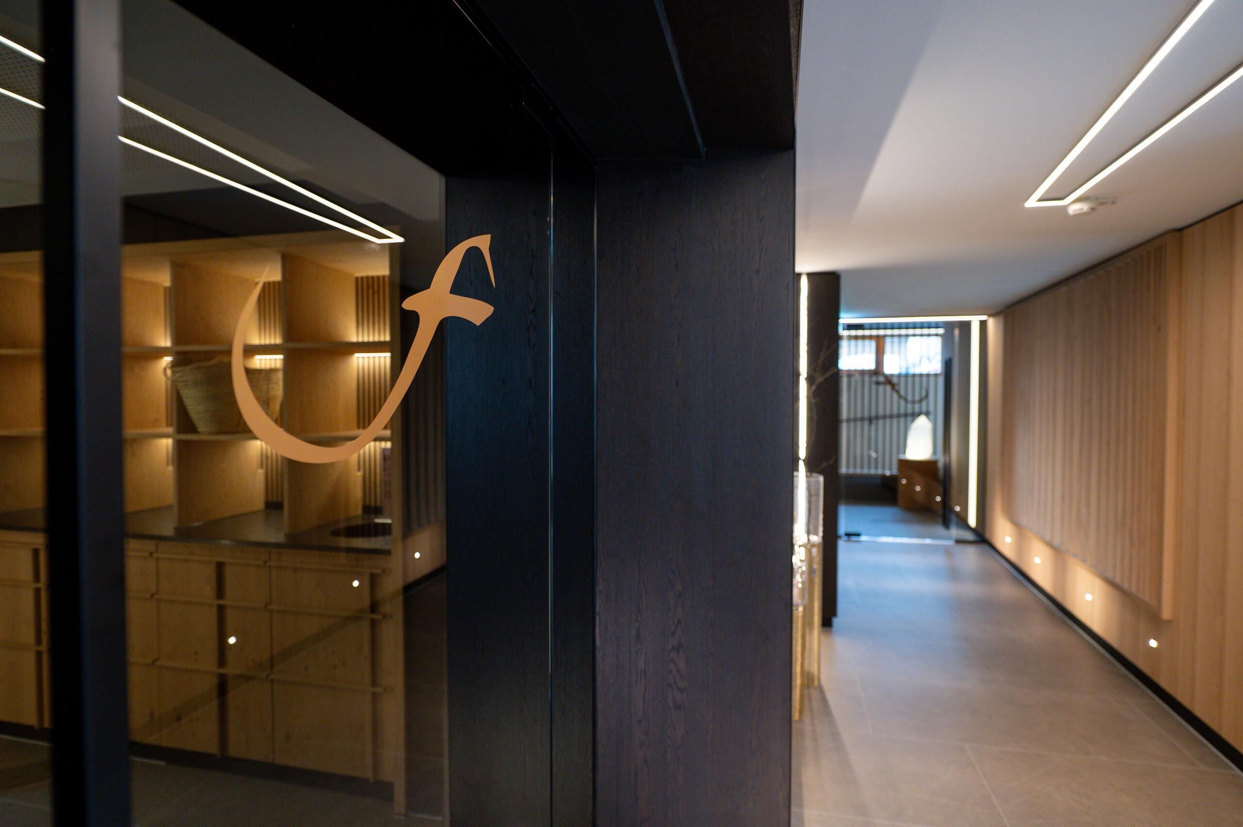 Um interior moderno com design de parede curva, uma coluna central e um corredor longo que leva a uma escada.