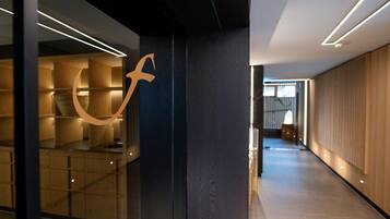 Um interior moderno com design de parede curva, uma coluna central e um corredor longo que leva a uma escada.