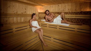 A sauna with wooden benches and a stone wall. - Bio Thermalhotel Falkenhof (Bad Fuessing)