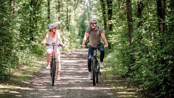 Två personer cyklar på en grusväg som omges av träd.