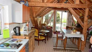 Una cocina acogedora tipo buhardilla con vigas de madera, una zona de comedor con mesa y sillas, y vistas al exterior.