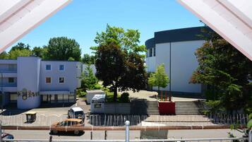 Un edificio moderno con fachada curva, zona de estacionamiento y un árbol frente a él.