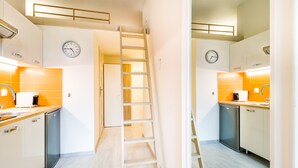 Una cocina moderna con armarios blancos, una escalera de madera y dos relojes en la pared.