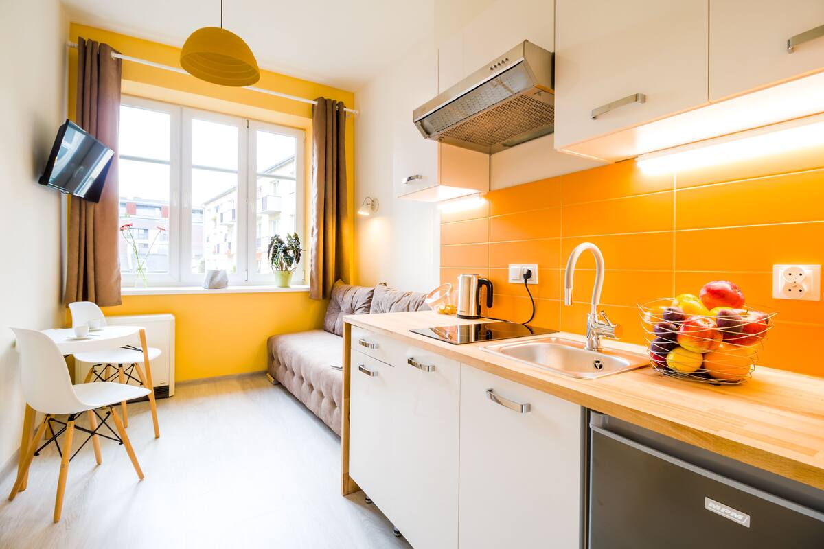 Una cocina moderna con encimera de madera, armarios blancos y un frutero.