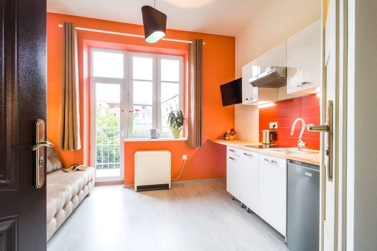 Una cocina moderna con armarios blancos, horno integrado y una ventana con cortinas.
