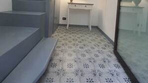 A staircase with a modern design, a small table with a lamp, and patterned floor tiles. - Old renovated studio apartment in Town Hall Square with works on display (Agrigento)