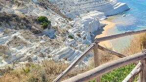 A coastal landscape with white cliffs, a sandy beach, and a wooden fence. - Old renovated studio apartment in Town Hall Square with works on display (Agrigento)