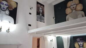 A room with a white ceiling, a white wall, and a white floor. There is a white shelf with a white object on it. There is a white curtain on the window. There is a white light fixture on the wall. There is a white door. There is a white wall sconce. There is a white wall sconce. There is a white wall sconce. There is a white wall sconce. There is a white wall sconce. There is a white wall sconce. There is a white wall sconce. There is a white wall sconce. There is a white wall sconce. There is a white wall sconce. There is a white wall sconce. There is a white wall sconce. There is a white wall sconce. There is a white wall sconce. There is a white wall sconce. There is a white wall sconce. There is a white wall sconce. There is a white wall sconce. - Old renovated studio apartment in Town Hall Square with works on display (Agrigento)