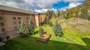 A hotel courtyard with a fenced deck, surrounded by trees and a building with multiple windows. - Amazing Views, free wifi, free parking. Industrial Cozy Telemark Lodge studio (Copper Mountain)