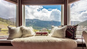 A bed with a fluffy white cover and pillows, a sign reading "Ski Area", and a view of mountains and a village through large windows. - Amazing Views, free wifi, free parking. Industrial Cozy Telemark Lodge studio (Copper Mountain)