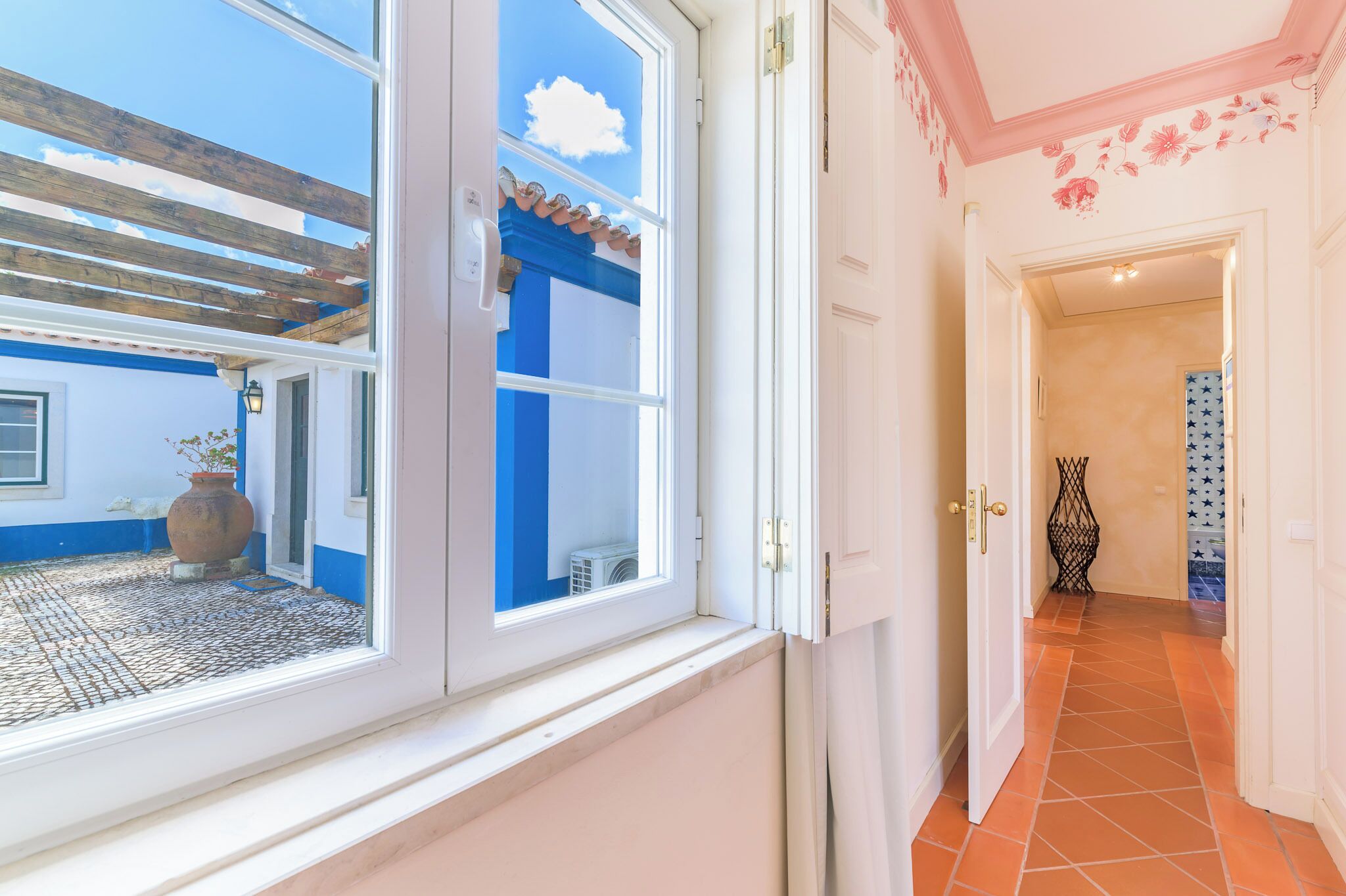 A room with a large window, a door leading to a hallway, and a tiled floor.