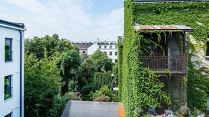 A building with a green ivy-covered exterior, a visible rooftop, and a view of surrounding buildings and trees. - Aparthotel Cracovia Residence (Kraków)
