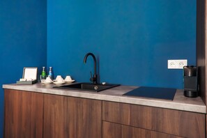 Una cocina moderna con un lavamanos negro, armarios de madera y una pared azul.