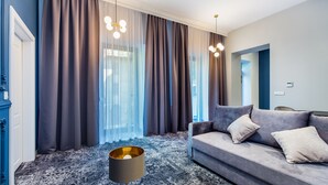 A modern living room with a grey sofa, a wooden coffee table, and a patterned carpet. - Aparthotel Cracovia Residence (Kraków)