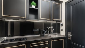 A modern kitchen with dark cabinetry, a stainless steel countertop, and a built-in stove. - Rai Apartments (Odesa)