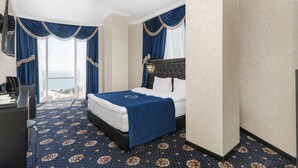 A hotel room with a bed, a desk, and a view of the sea. - Rai Apartments (Odesa)