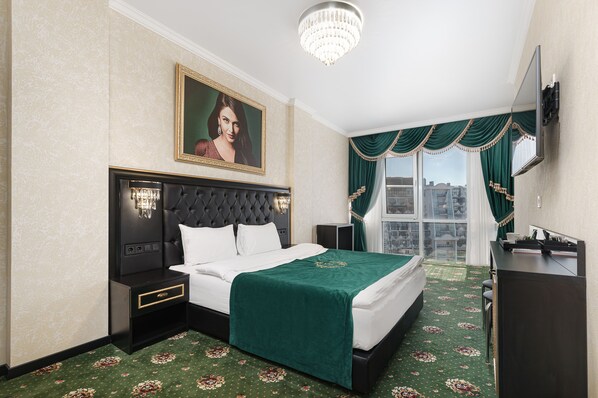 A hotel room with a large bed, a nightstand, a dresser, a television, and a window with curtains.