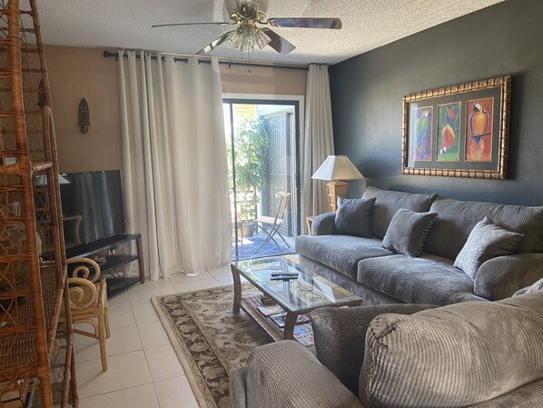 A living room with a sofa, a coffee table, a TV, and a ceiling fan.