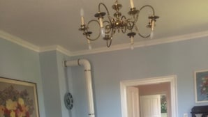 Uma sala de estar com lareira, uma poltrona estampada, uma mesa de centro de madeira e um candelabro.
