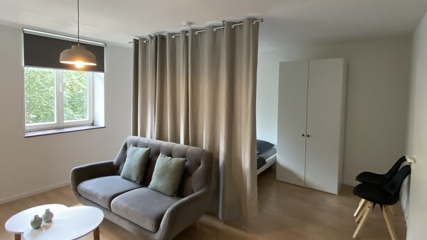 A modern living room with a grey sofa, a small white table, and a black chair.