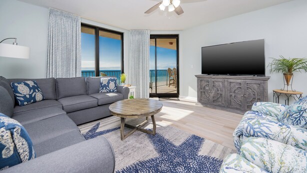 A modern living room with a grey sofa, a round coffee table, and a television on a cabinet. - Phoenix X 714 - Beautiful 3BR Gulf Front Unit (Orange Beach)
