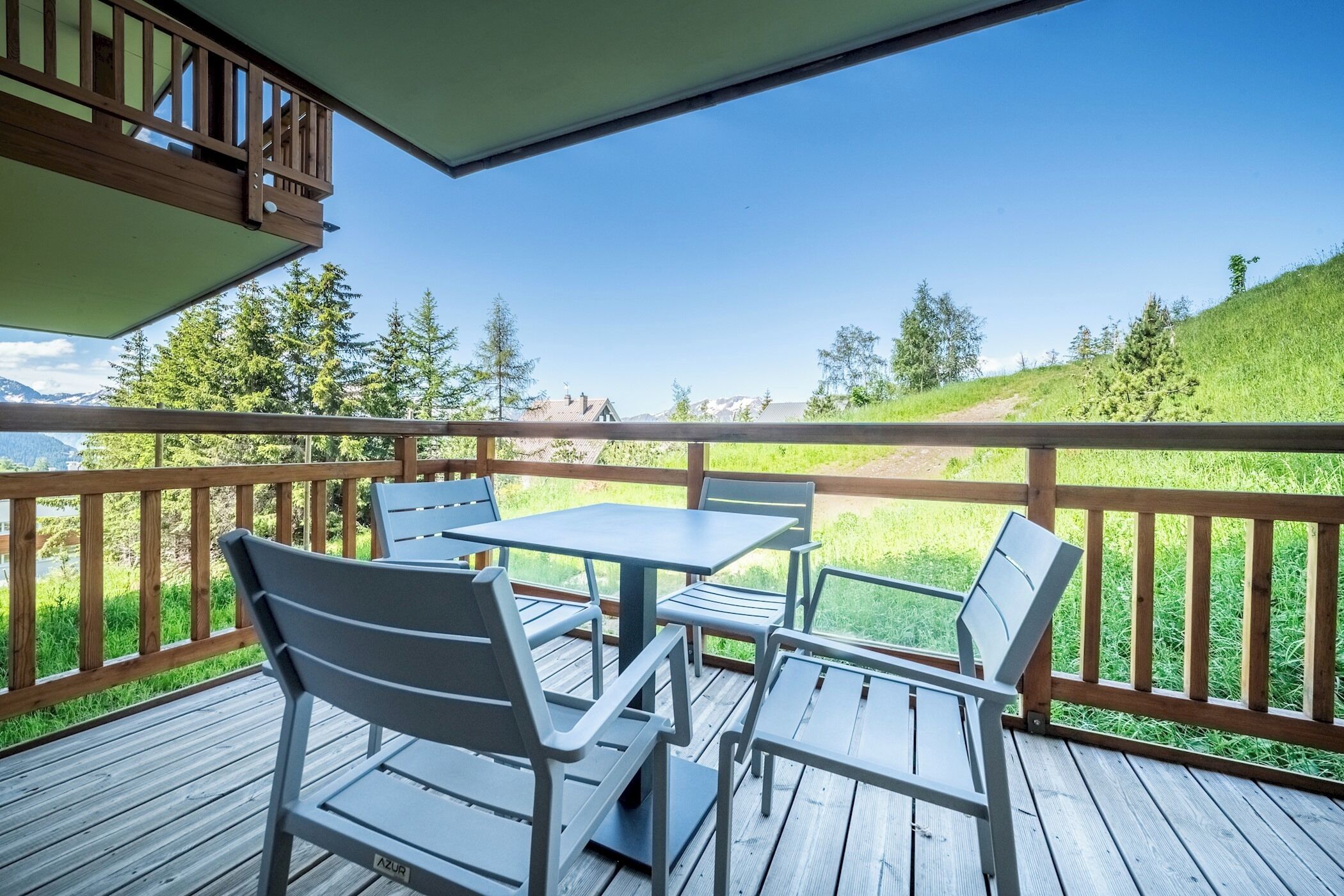 Une terrasse en bois avec une table et des chaises, donnant sur une pelouse et des arbres.