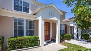 A two-story house with a front porch, large windows, and a well-maintained lawn. - Windsor Palms-ru556 (Kissimmee)