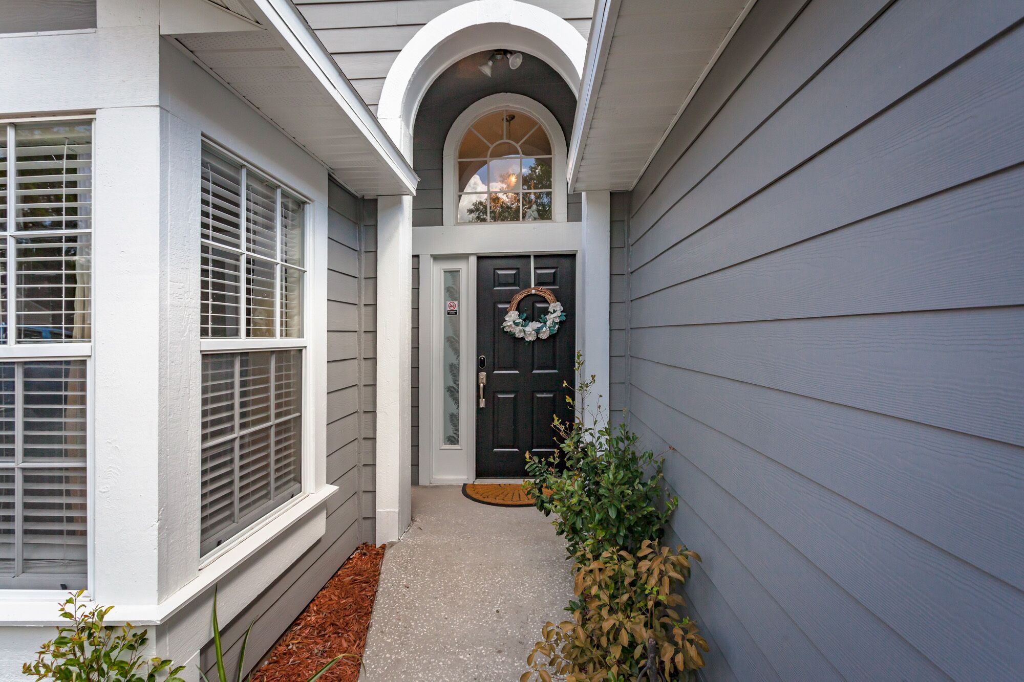 A house with a dark front door, a small porch, and a window with blinds.