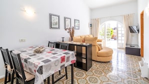 Un coin repas avec une table dressée pour deux personnes, un canapé et un téléviseur dans le salon.