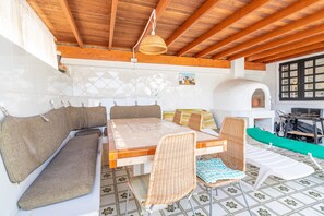A cozy outdoor seating area with a wooden ceiling, a table, and wicker chairs.