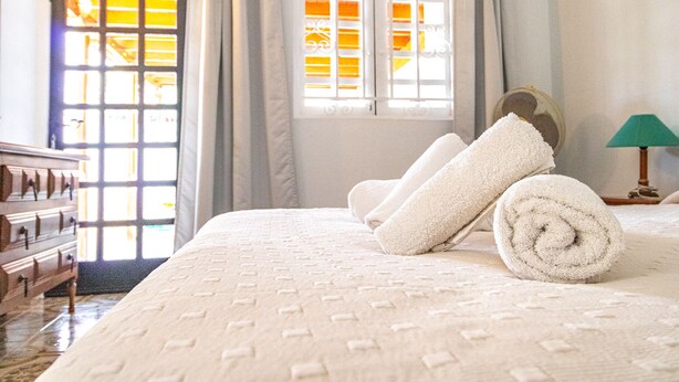 Une chambre d’hôtel avec un lit, une fenêtre avec des rideaux et une lampe.
