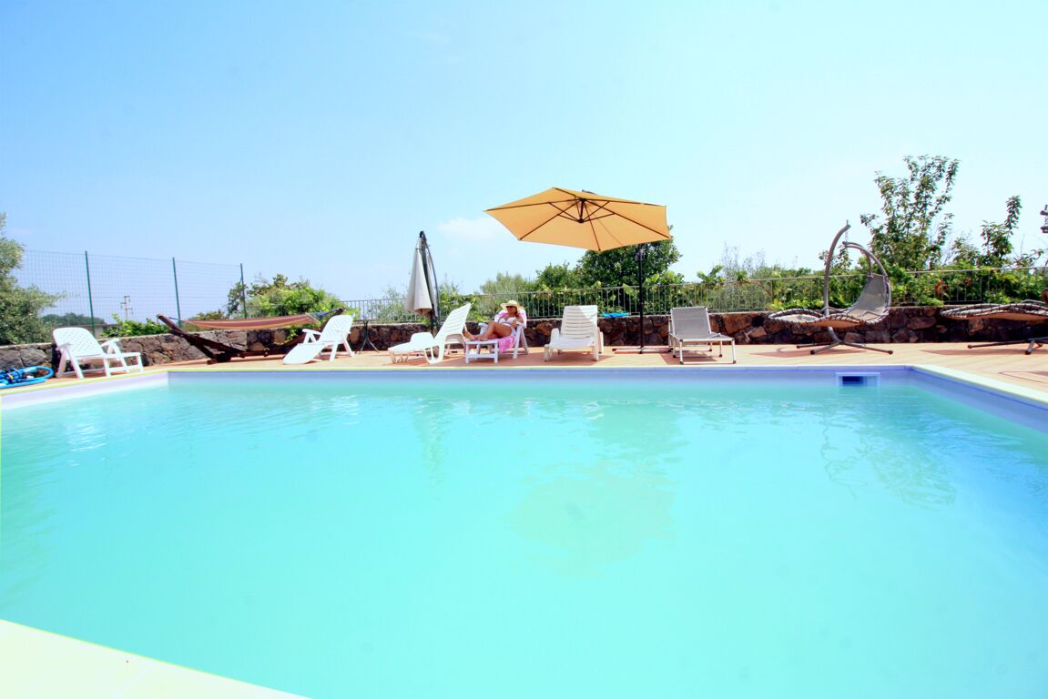 Une piscine avec des chaises longues et un parasol.
