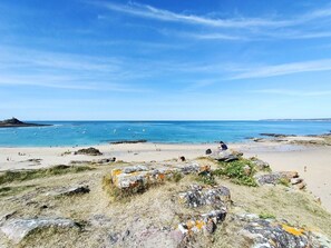 Une plage au paysage rocheux, bordée d’eaux d’un bleu limpide.