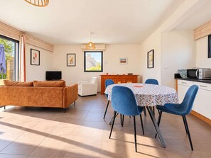 Un salon moderne comprenant un canapé, une table à manger avec des chaises, un coin cuisine avec un four à micro-ondes et des œuvres d’art accrochées aux murs.