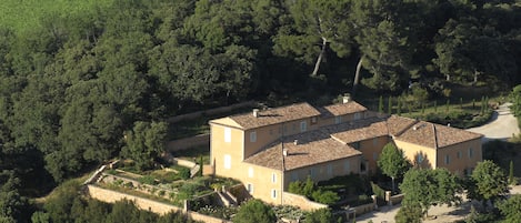 A large, multi-story building with a courtyard, surrounded by dense forest.