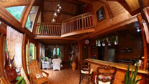 L’intérieur d’un chalet en bois comprend un coin repas, une cuisine et un balcon doté d’une balustrade.