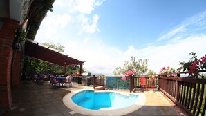 Une piscine dotée d’une terrasse carrelée, entourée de mobilier d’extérieur et d’une pergola en bois.