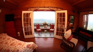 Une cabane en bois avec un balcon, un lit, un canapé et une télévision.